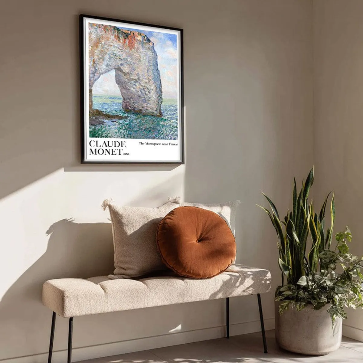 Framed coastal arch artwork displayed above a bench beside indoor plants