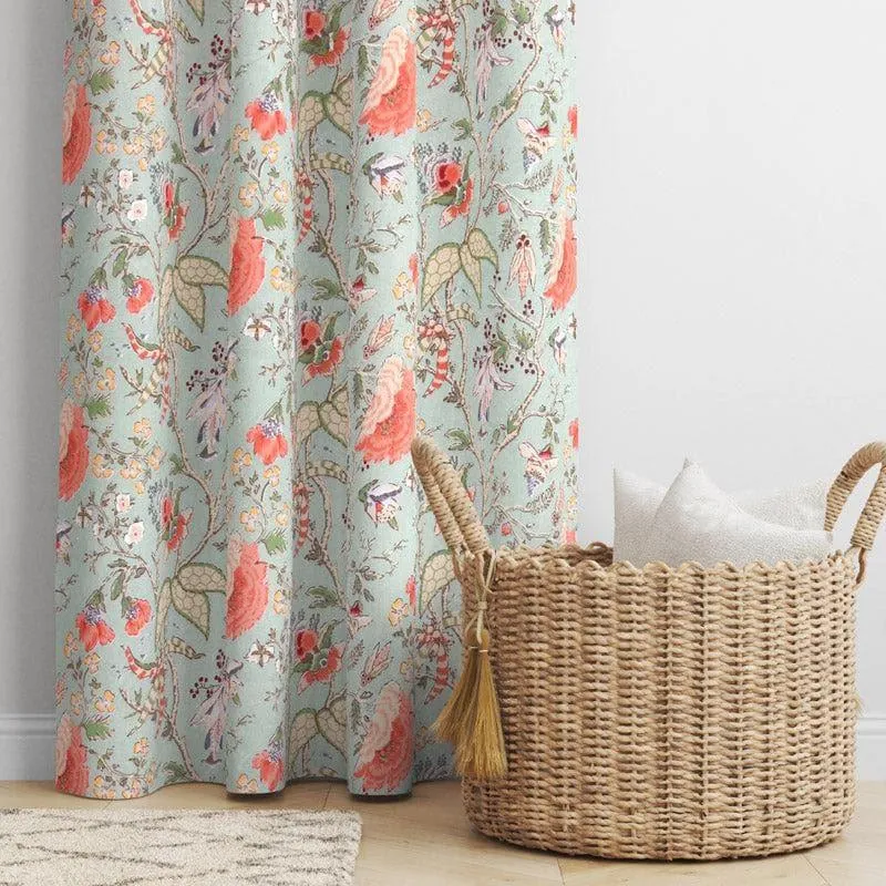 Pale aqua floral curtain beside a woven basket in a softly styled room.