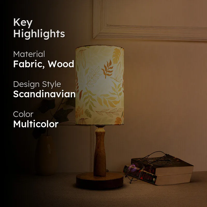 Lit table lamp with leafy shade and wooden base in a warm interior setting