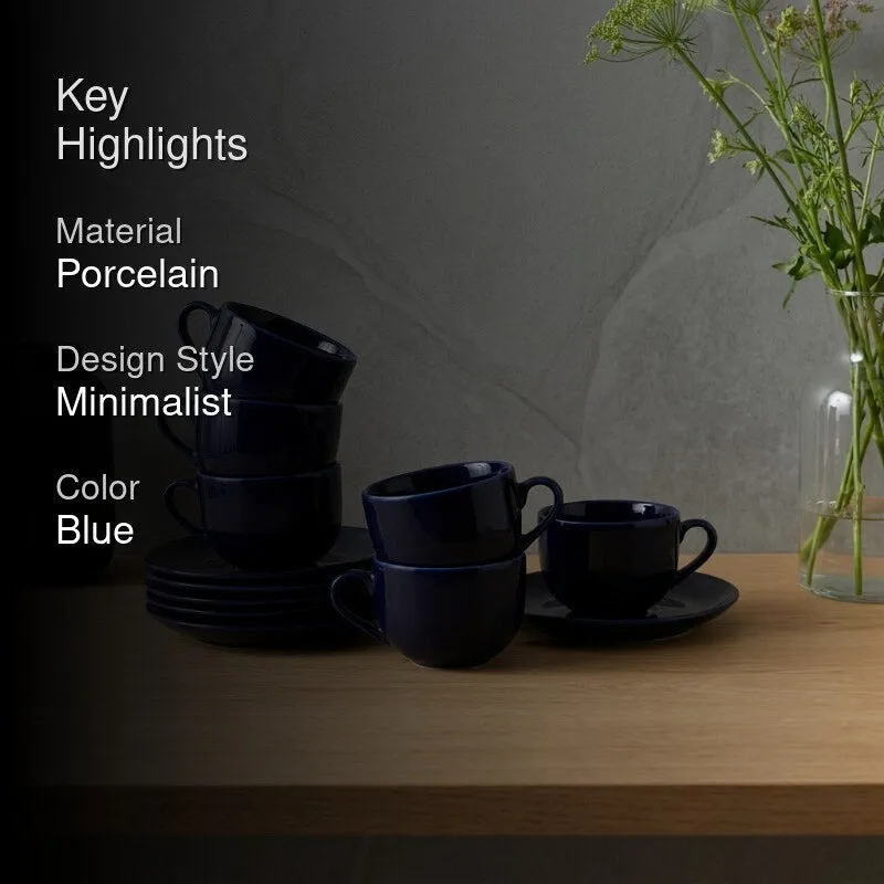 Blue cup and saucer set styled on a table beside a vase of flowers