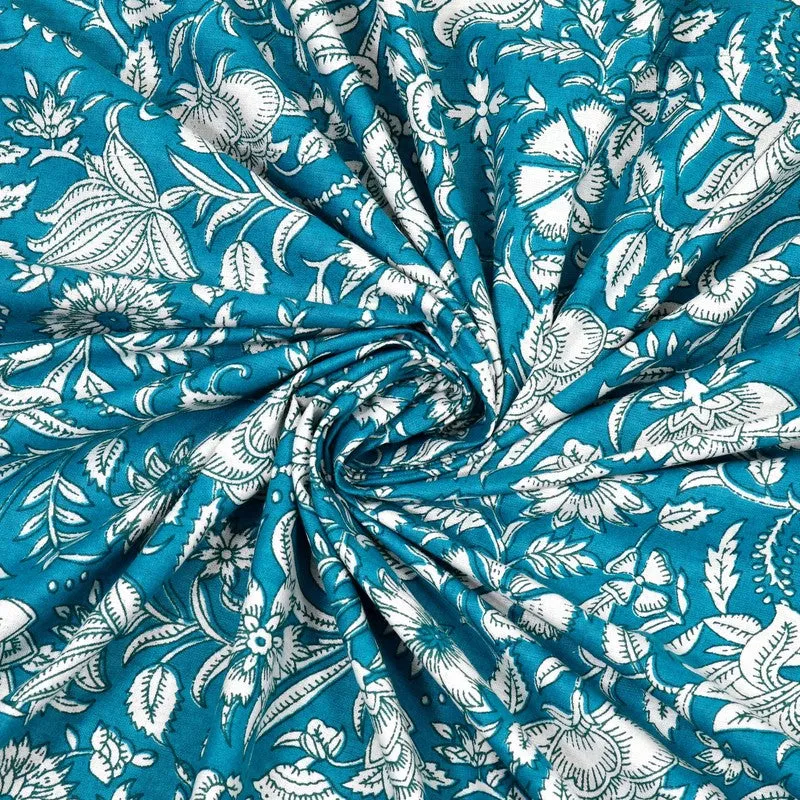 Close-up of teal fabric with a white floral pattern gathered in soft folds.