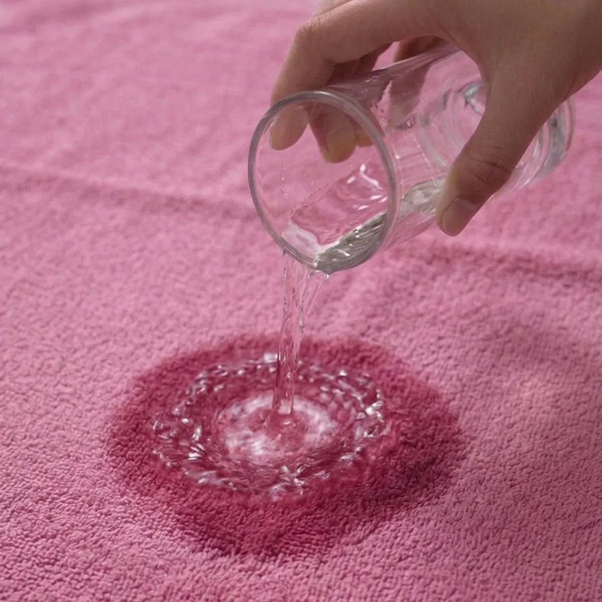 Water being poured onto a pink towel surface