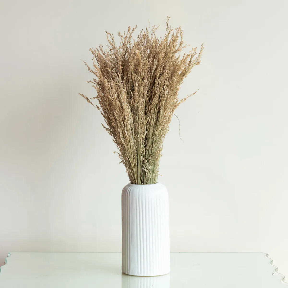 Brown dried grass arranged in a white ribbed vase