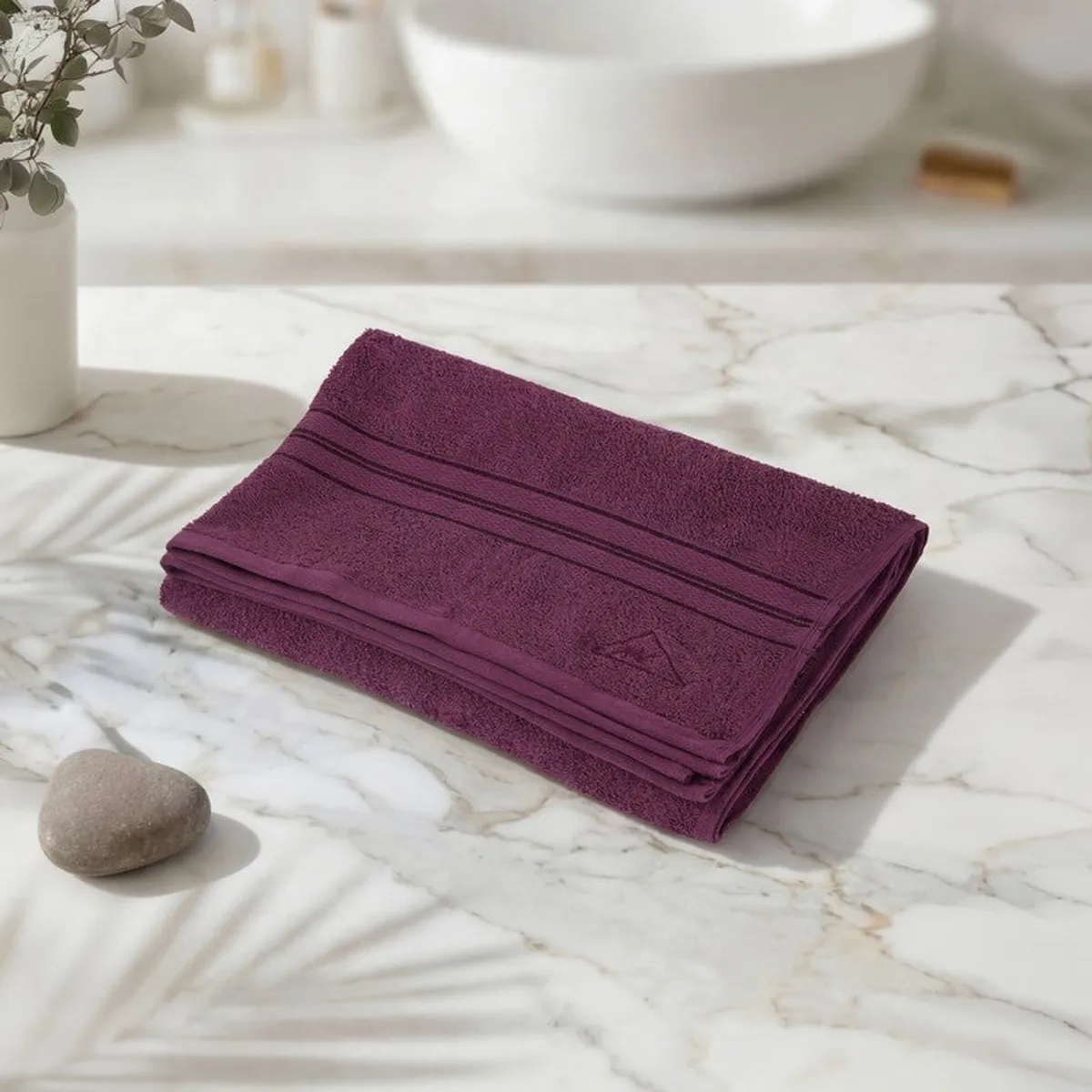 Folded wine-purple bath towel displayed on a marble surface