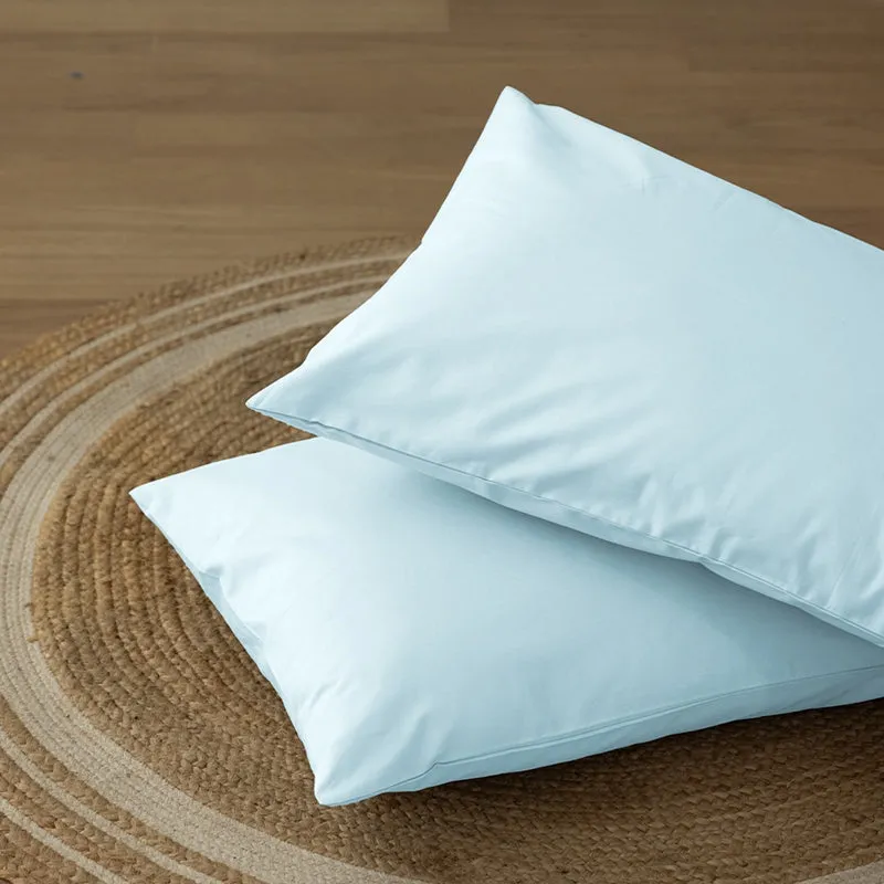 Two pale blue pillow covers placed on a round natural-fibre rug.