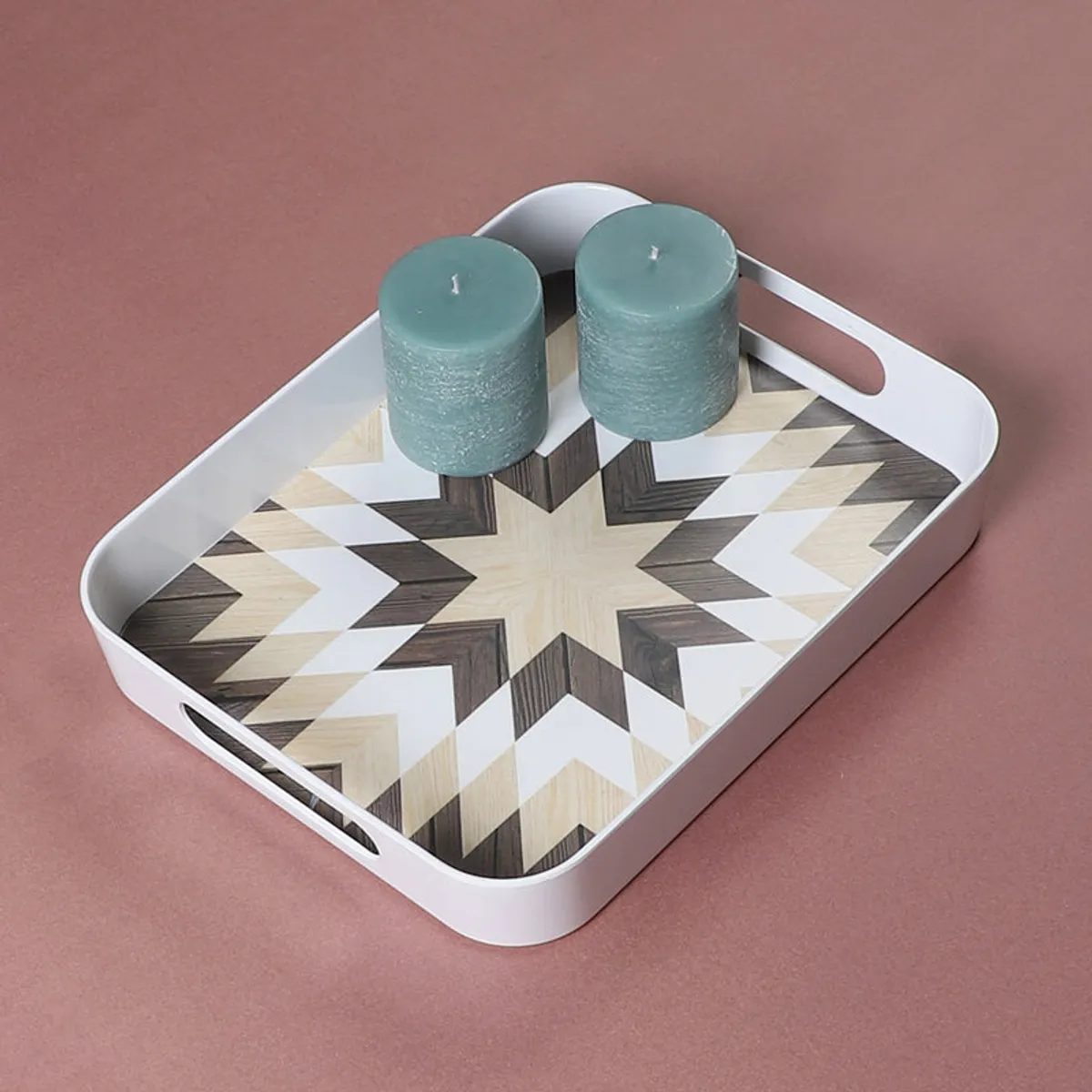 Geometric star-patterned serving tray holding two teal candles