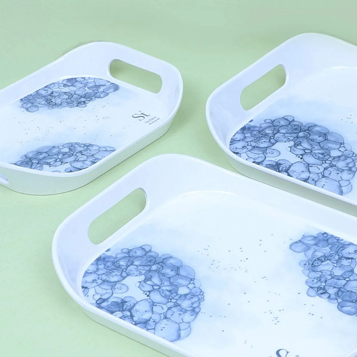 Three glossy white serving trays with blue floral detailing viewed from above.