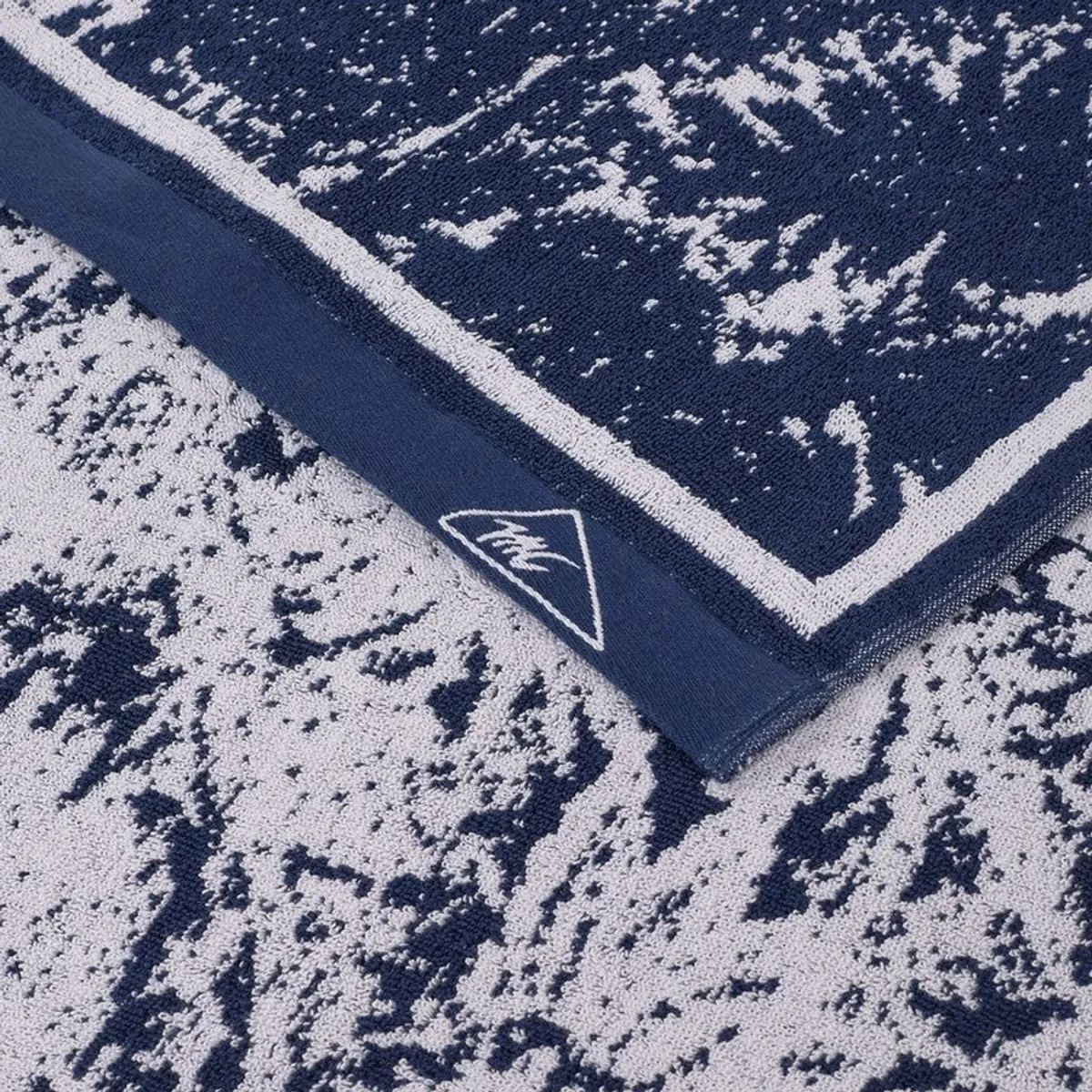 Close-up view of the towel's blue and white textured floral pattern and edging