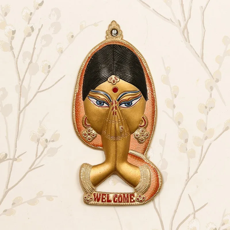 Front view of peach and gold greeting wall accent with folded hands motif