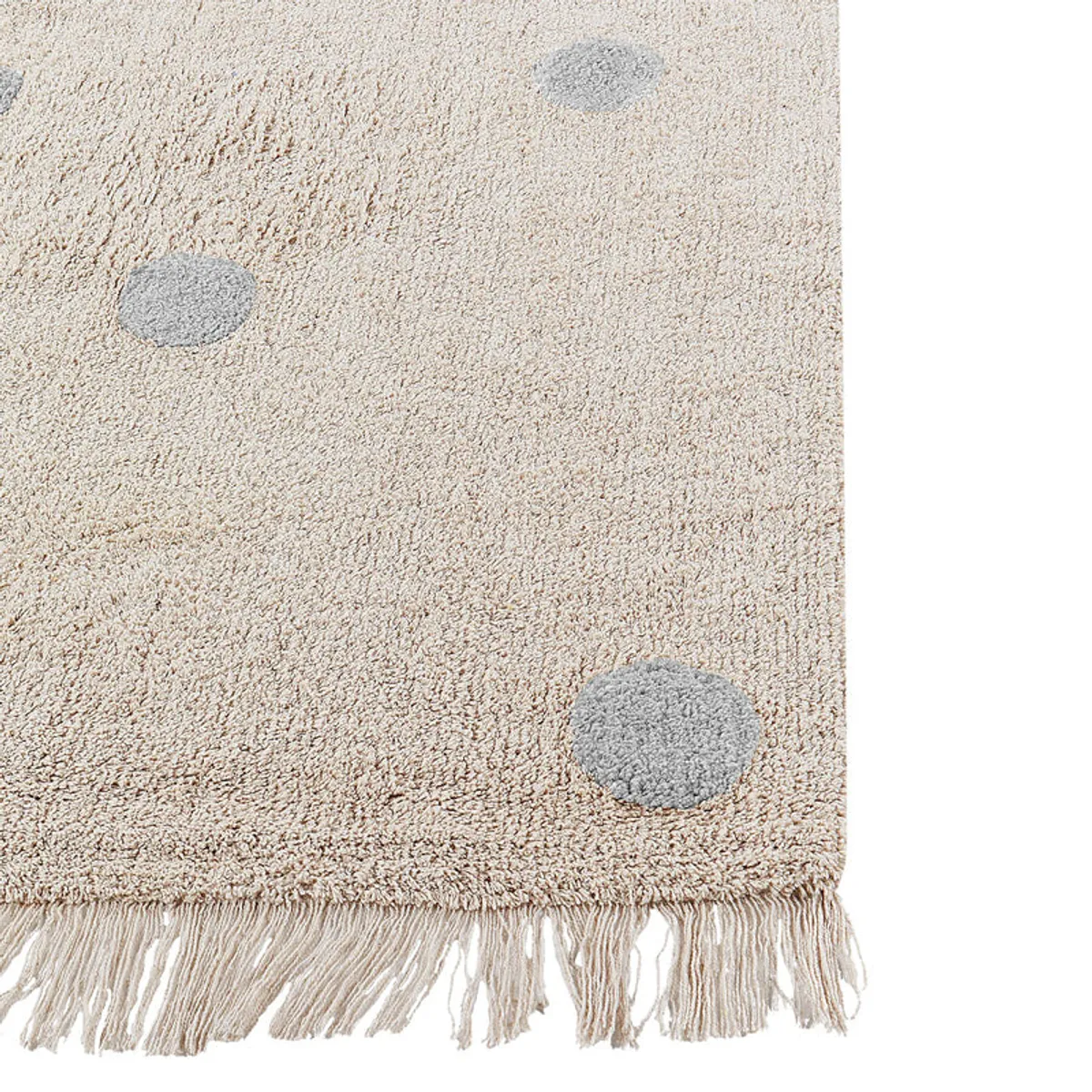 Close-up of a grey polka dot and fringed edge on the light rug