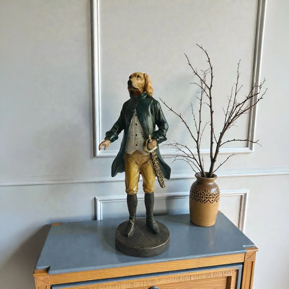 Aristocratic dog figurine on a console table beside a vase with branches