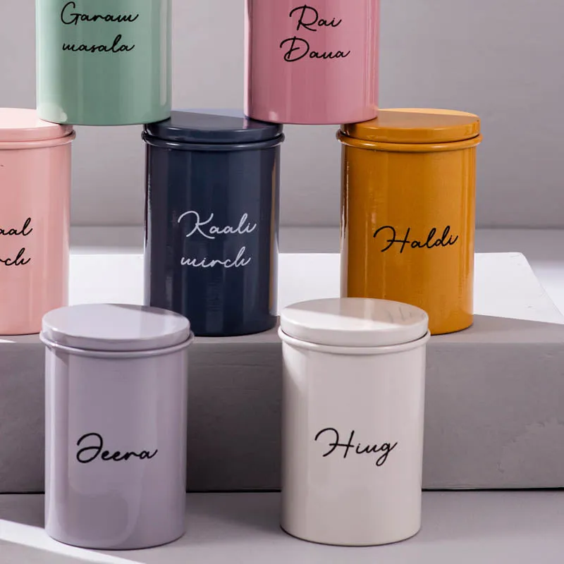 Close-up of colourful cylindrical jars with fitted lids and script labels