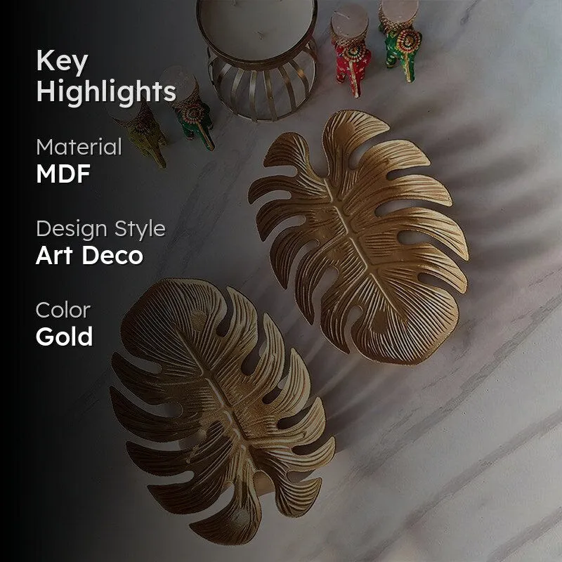 Two gold leaf-shaped platters displayed in a dimly styled setting