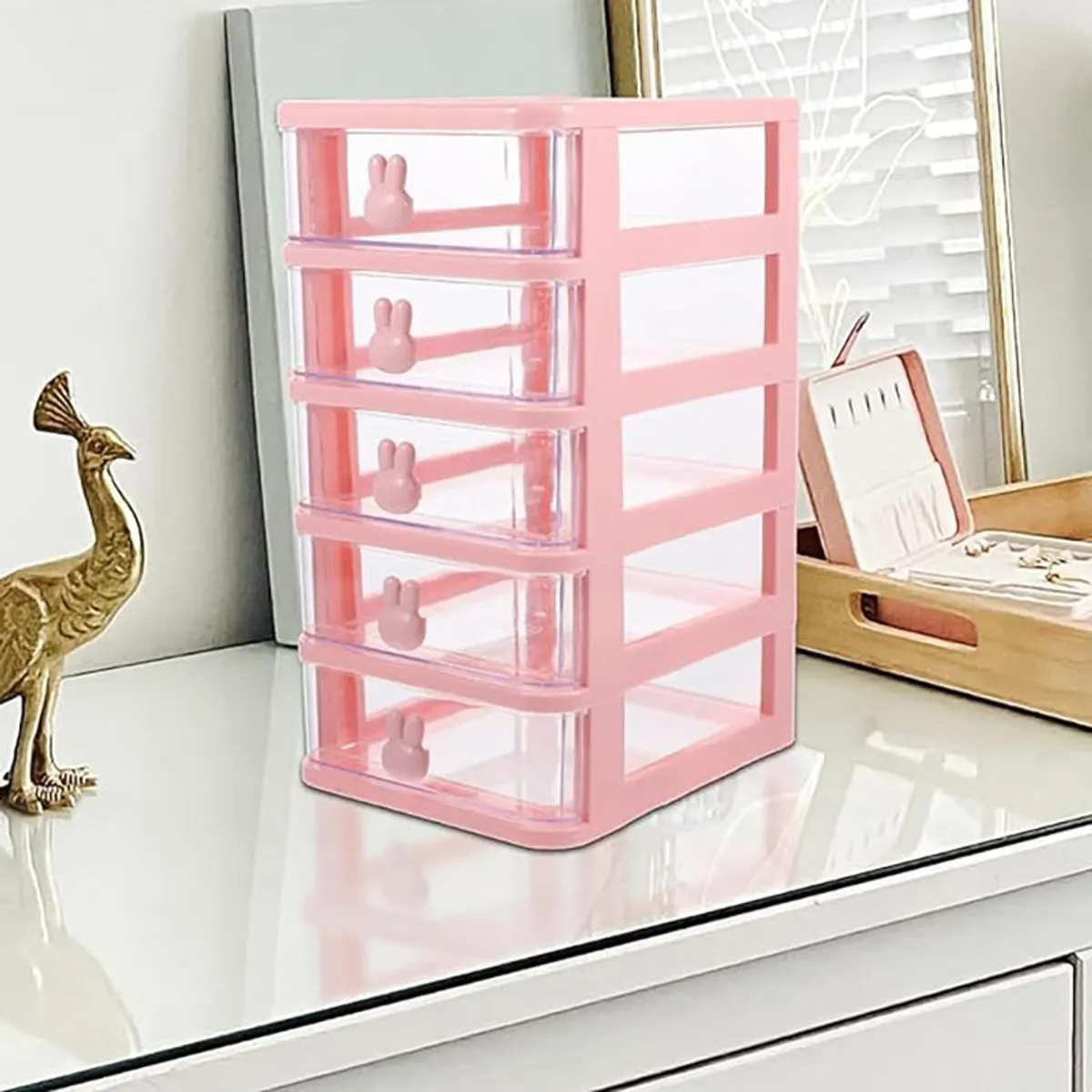 Pink five-tier organiser placed on a dressing table beside a jewellery box
