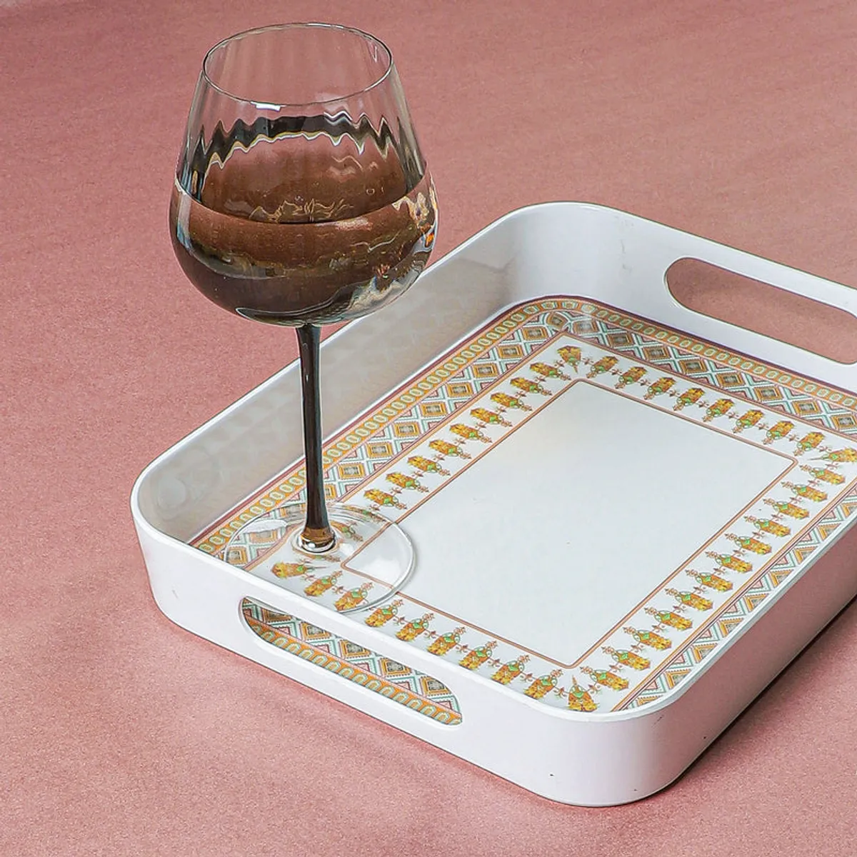 Close-up of patterned white serving tray with a glass placed on it
