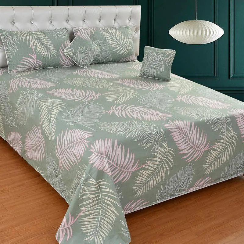 Green bedding set with pink and white leaf print on a bed