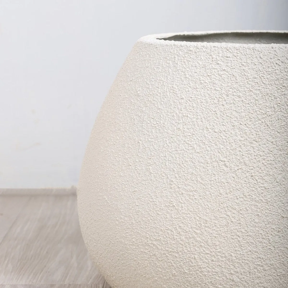 Close-up of the white planter showing its rounded free-form shape and open top