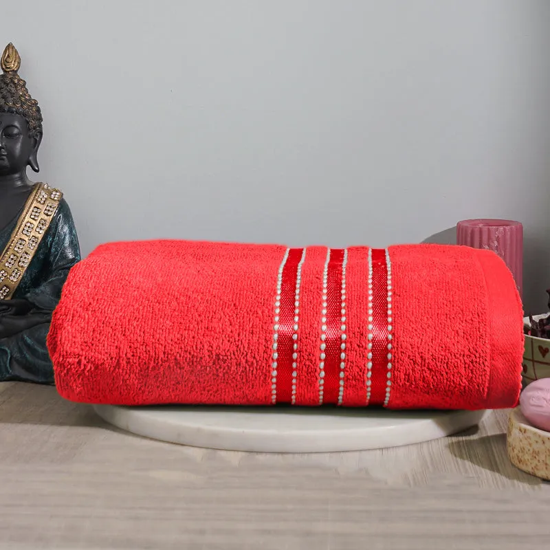 Rolled red bath towel with striped detailing displayed on a tray