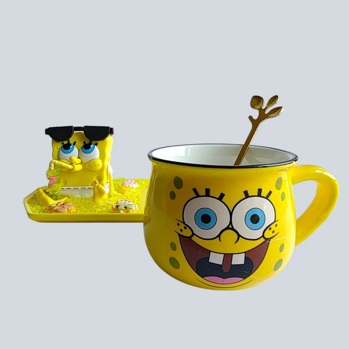 SpongeBob mug with gold-toned spoon beside a figurine