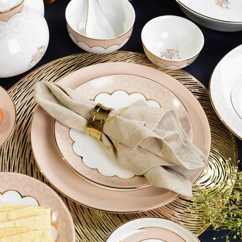 Layered peach and ivory plates with gold details styled on a dining table
