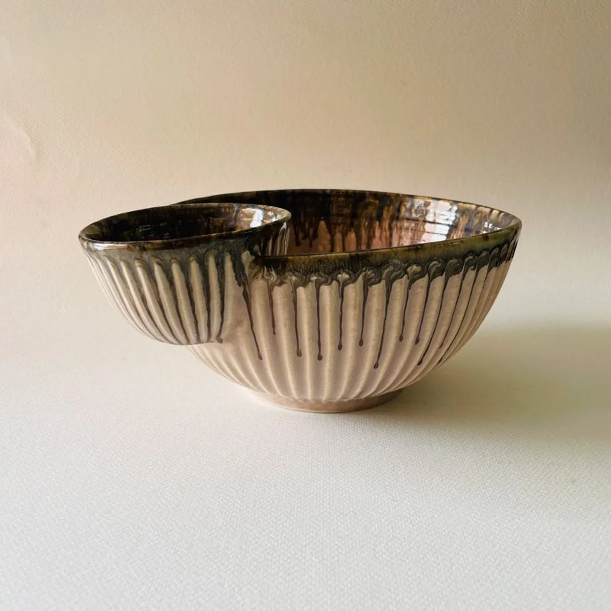Front view of a beige ceramic chip and dip bowl with ribbed sides
