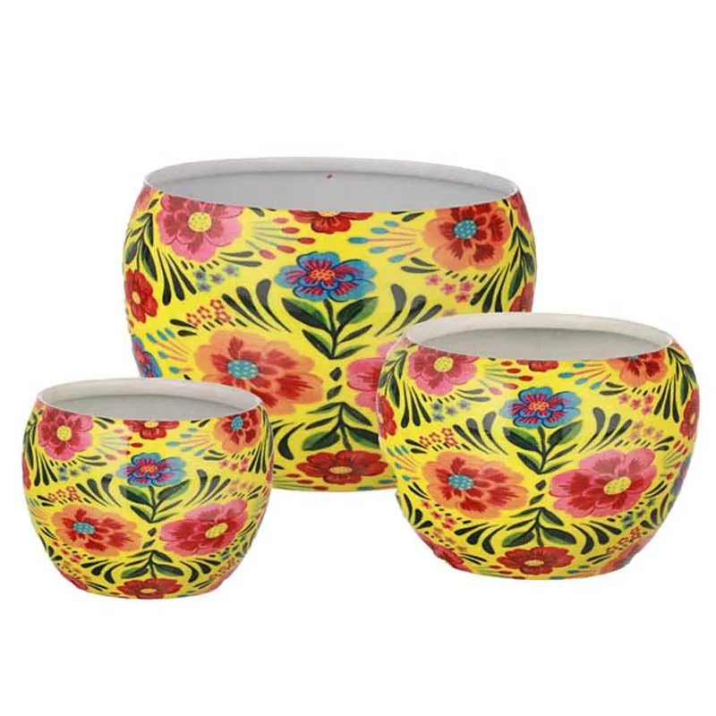 Set of three yellow floral metal planters on a white background