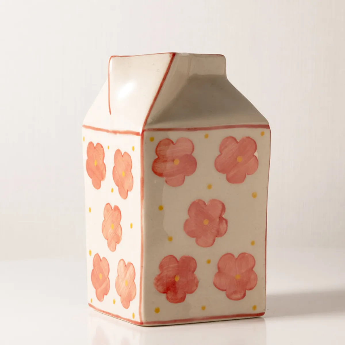 Studio view of the ceramic carton-shaped vase with pink floral pattern