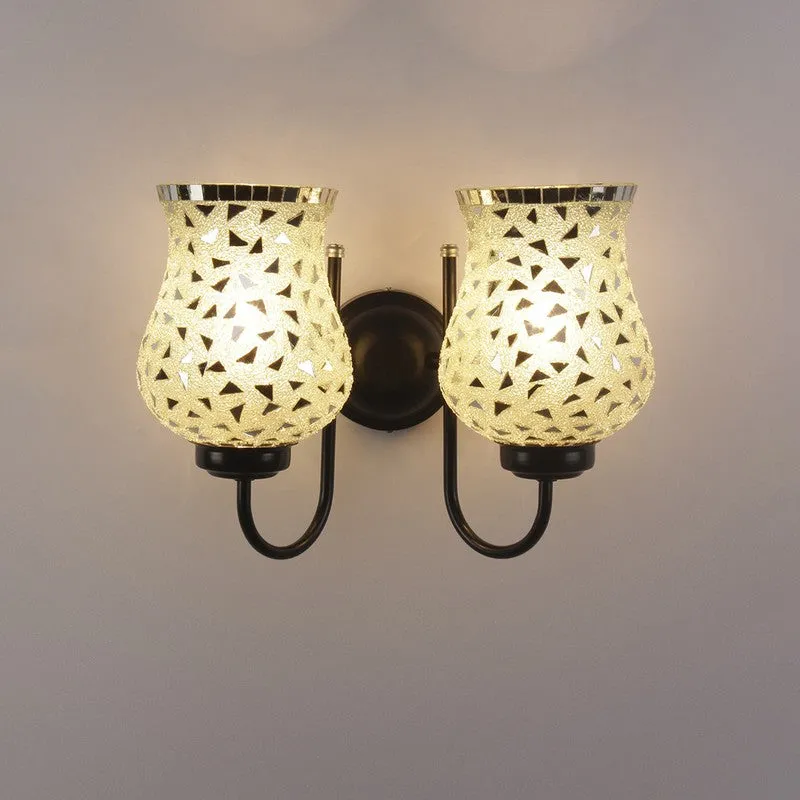 Dual wall lamp with glowing patterned glass shades on plain wall