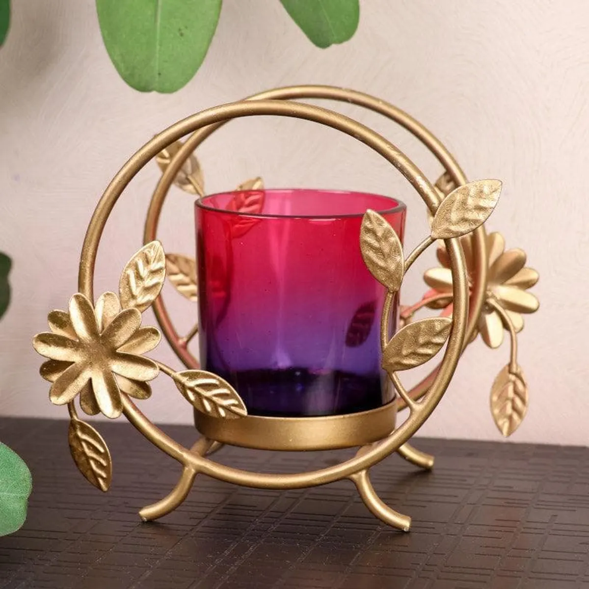 Angled view of gold floral spiral tealight holder with ombre glass cup