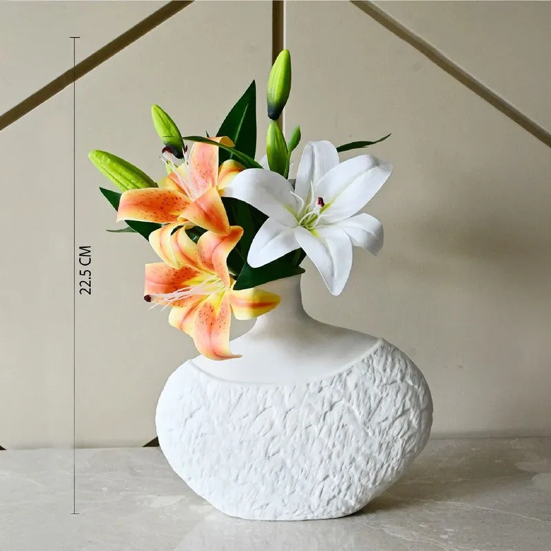 White textured vase styled with lilies on a stone surface.
