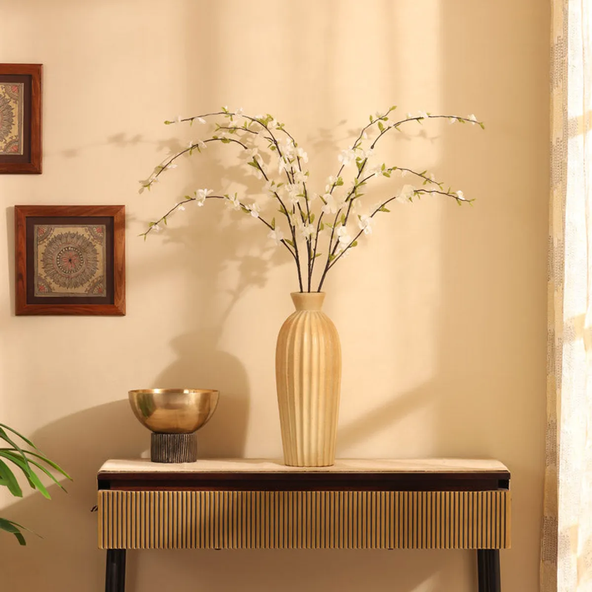 Tall vase with white artificial cherry blossom stems styled on a console table