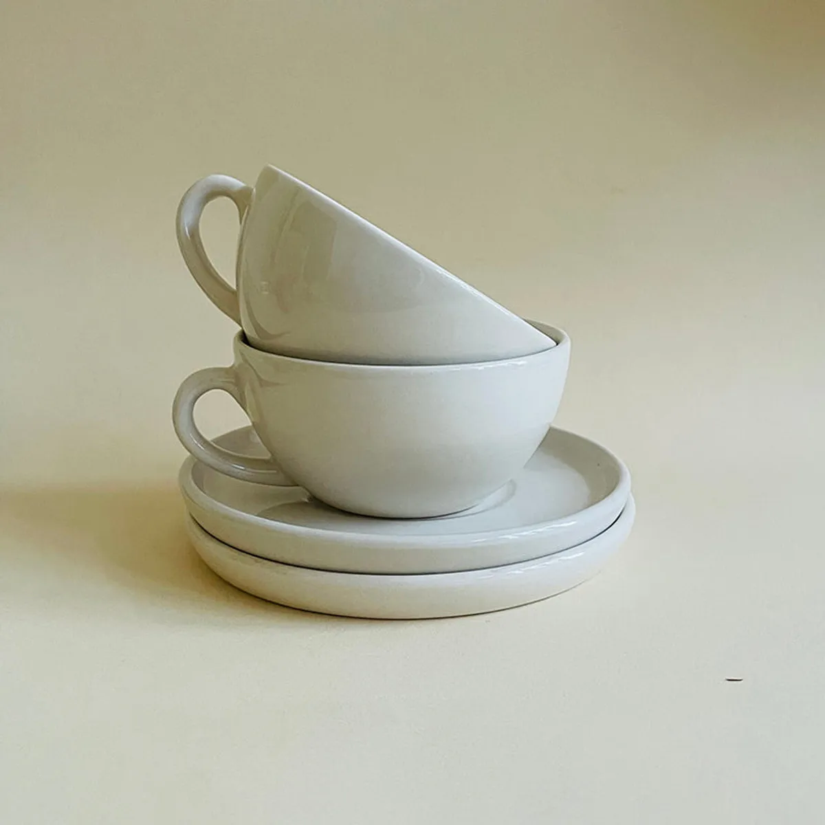 White ceramic cups stacked on saucers in a rounded minimalist design