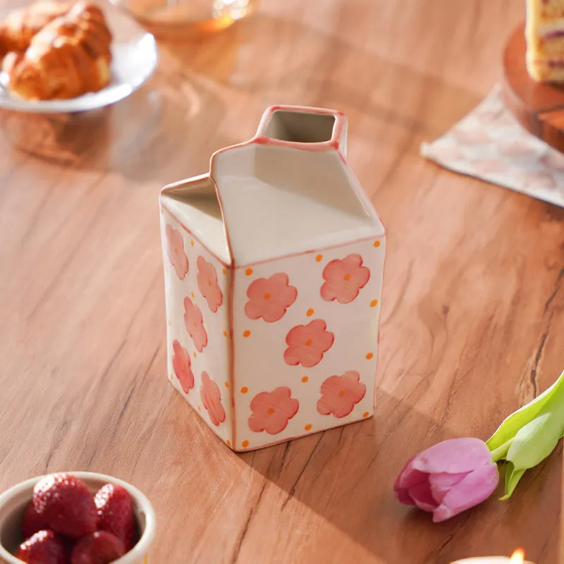 Angled view of a floral carton-shaped vase on a wooden table