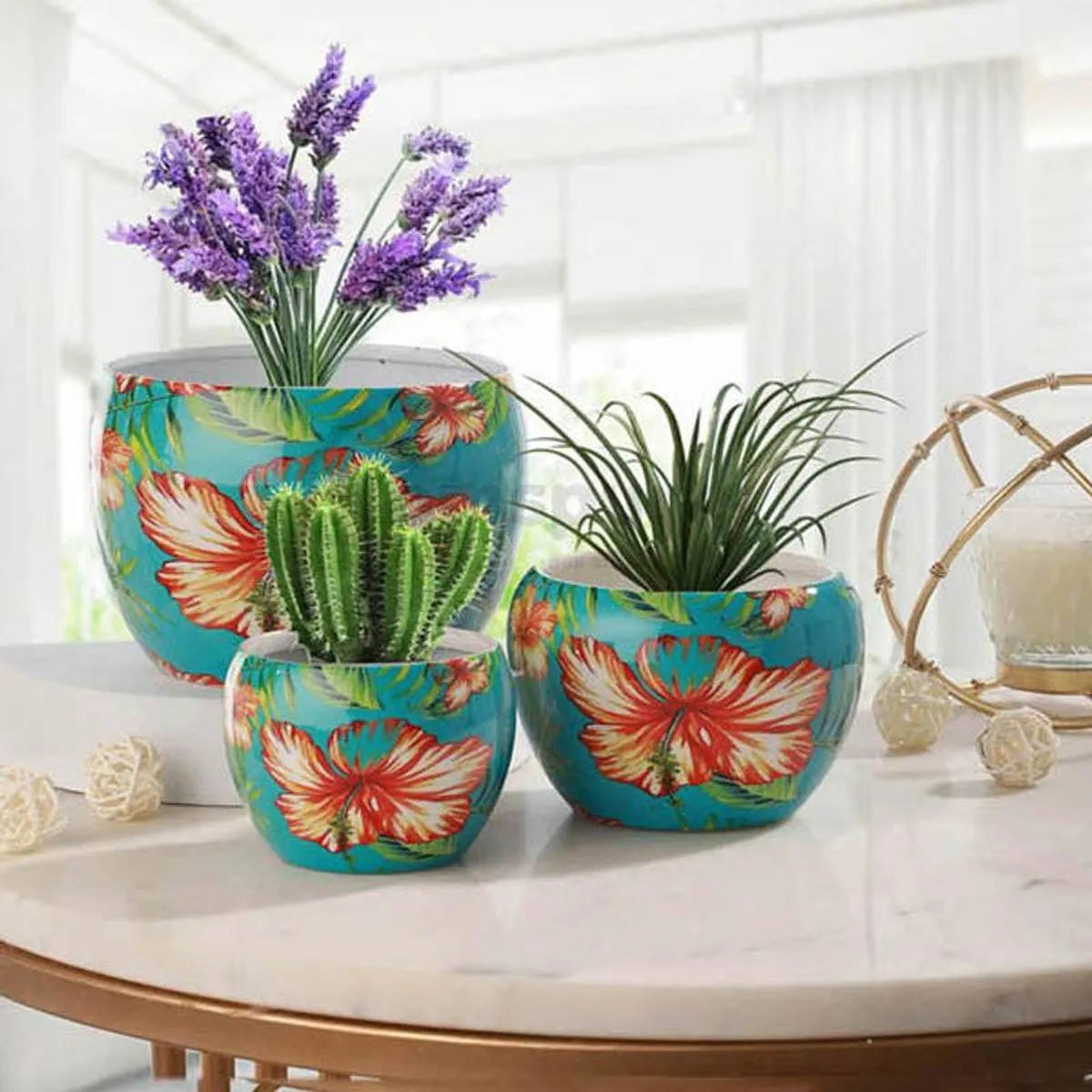 Three floral blue planters styled with plants on a round table