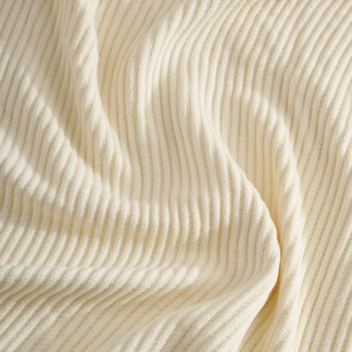 Close-up view showing the ivory throw's soft ribbed texture