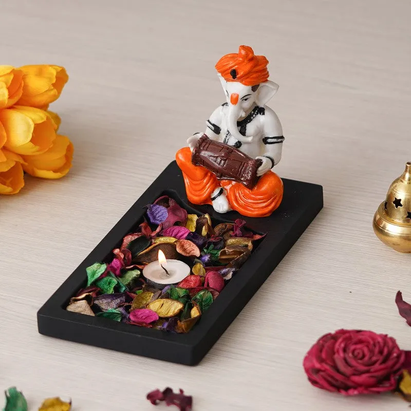 Angled view of Ganesha tea light holder with black base and orange-white figurine