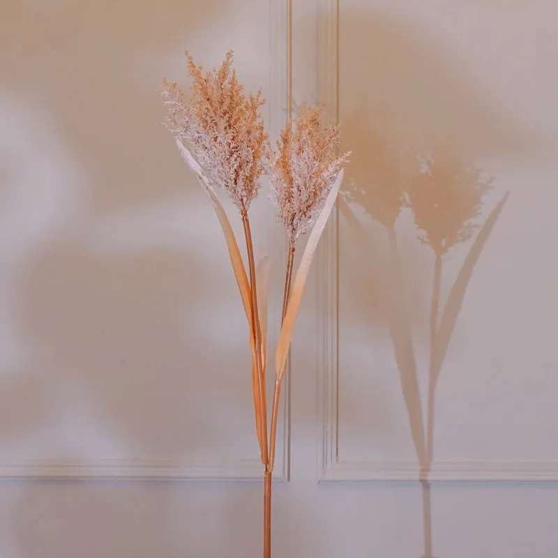 Beige faux pearl millet grass flower stick displayed against a light panelled wall