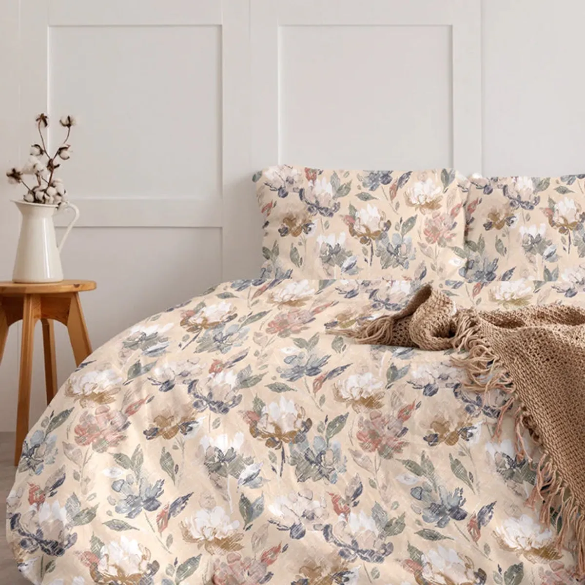 Floral beige duvet cover on a bed with a knitted throw and white panelling