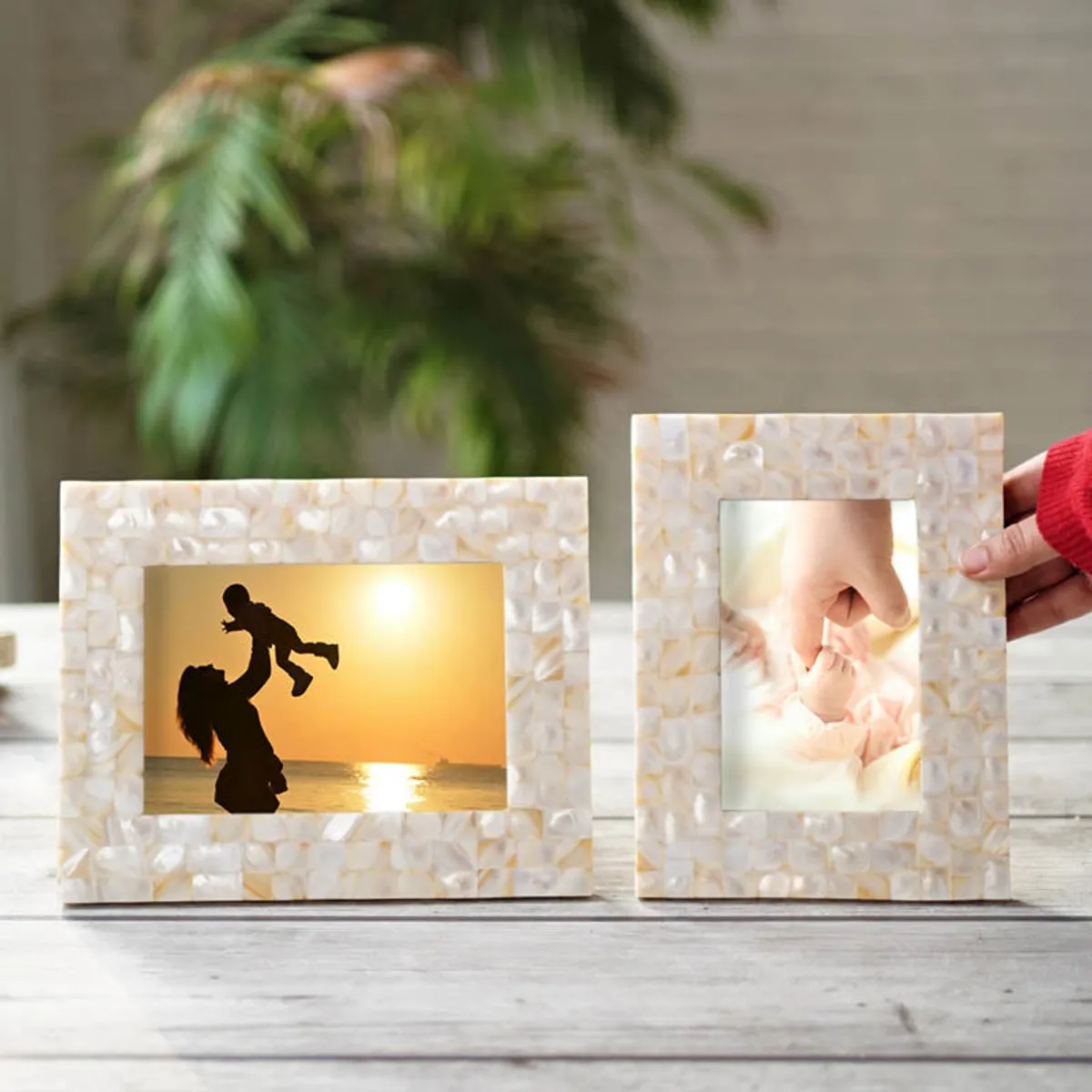 Two ivory pearl-mosaic frames displayed with family photographs on a tabletop.