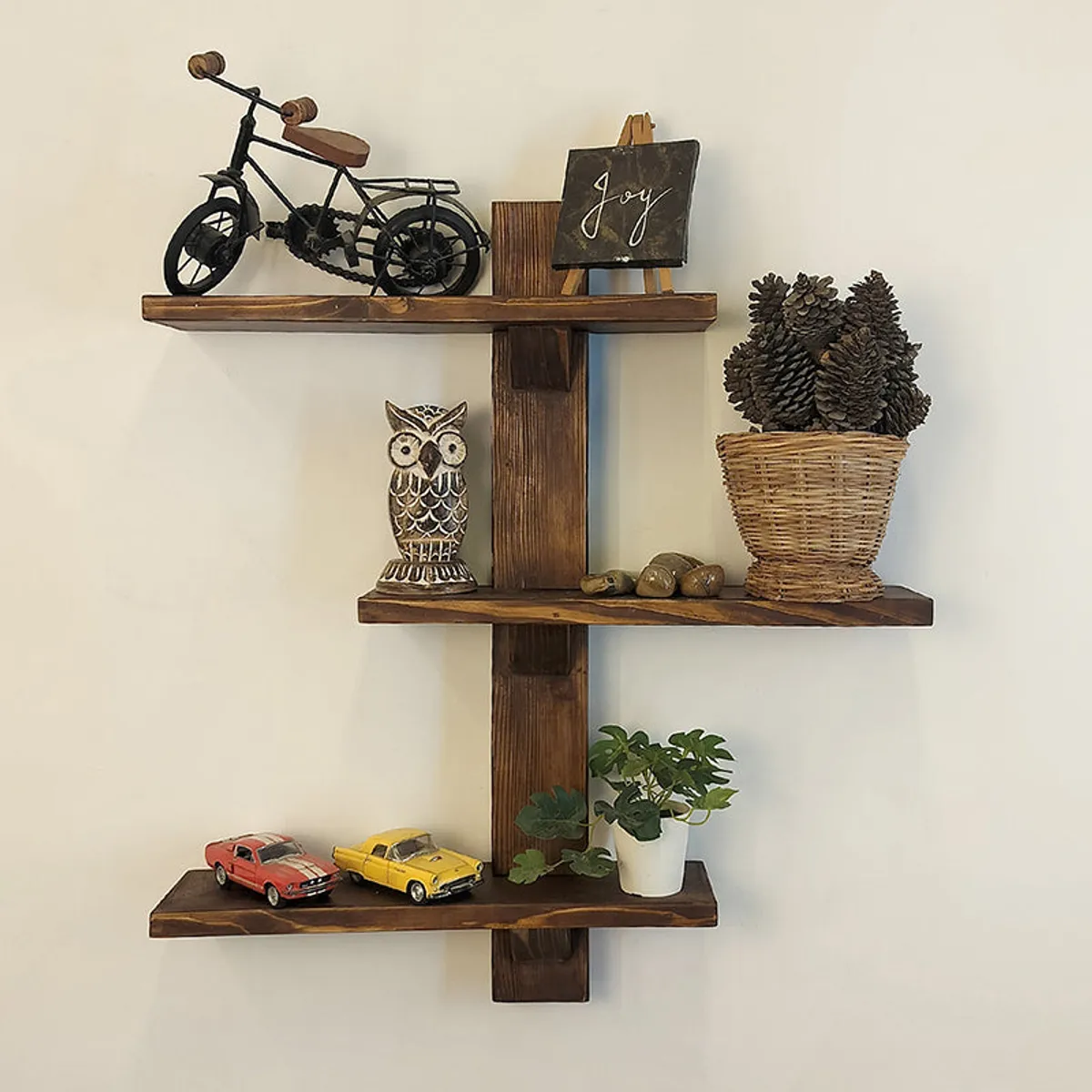 Front view of a brown three-tier wooden wall shelf with decorative objects.