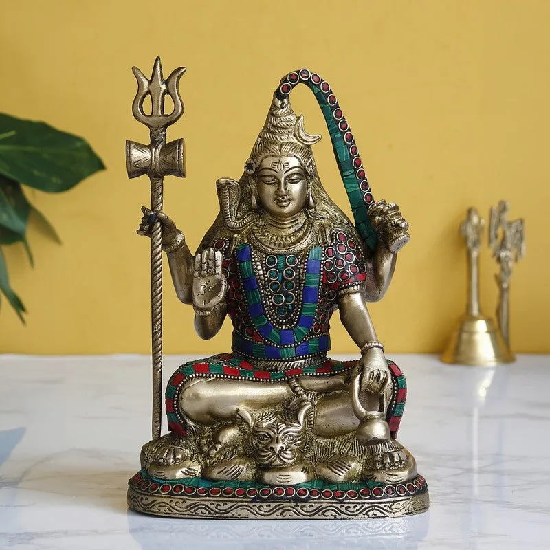 Brass-toned seated deity idol with colourful accents on a tabletop