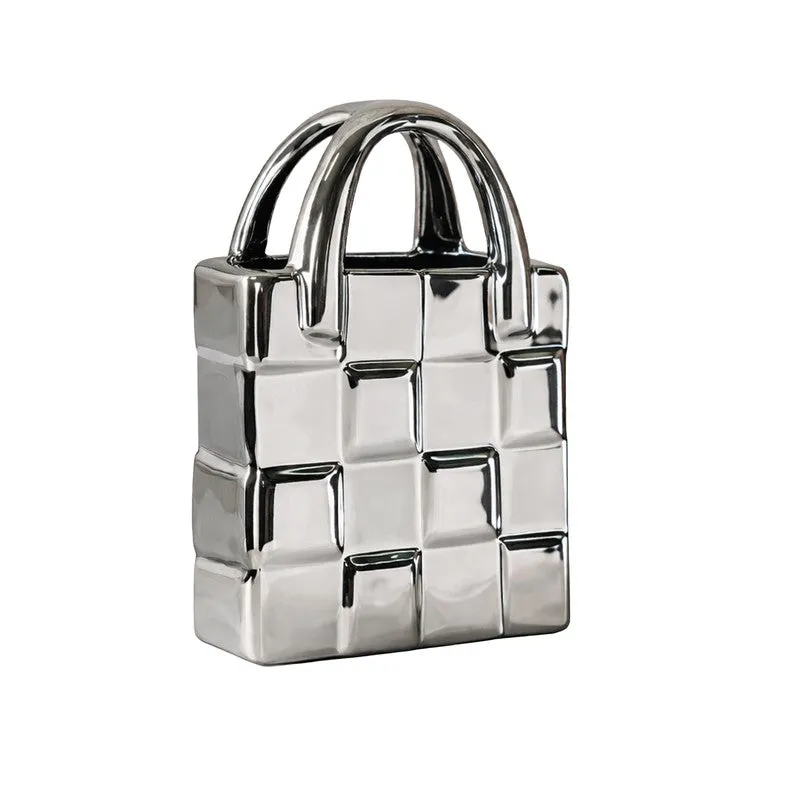 Studio view of a silver handbag-shaped ceramic vase on a white background