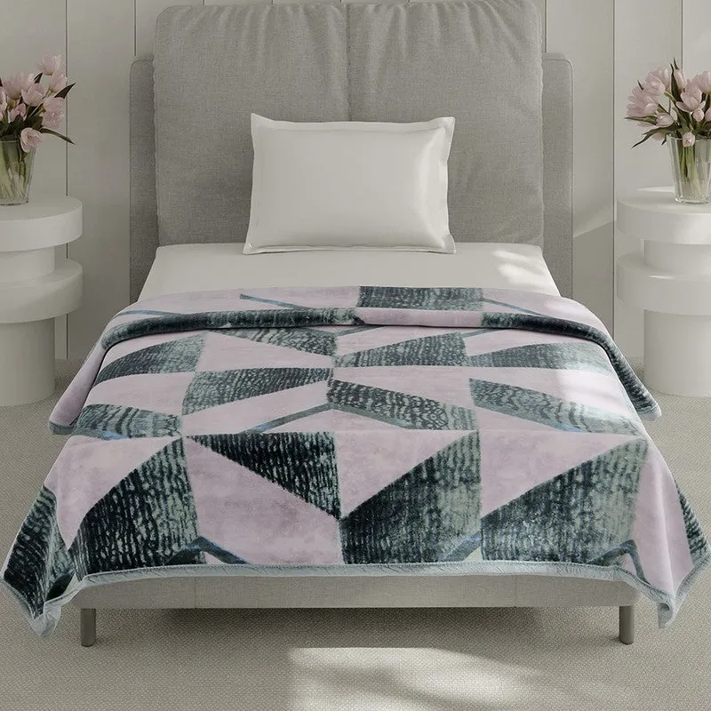 Geometric pink and green blanket draped over a single bed