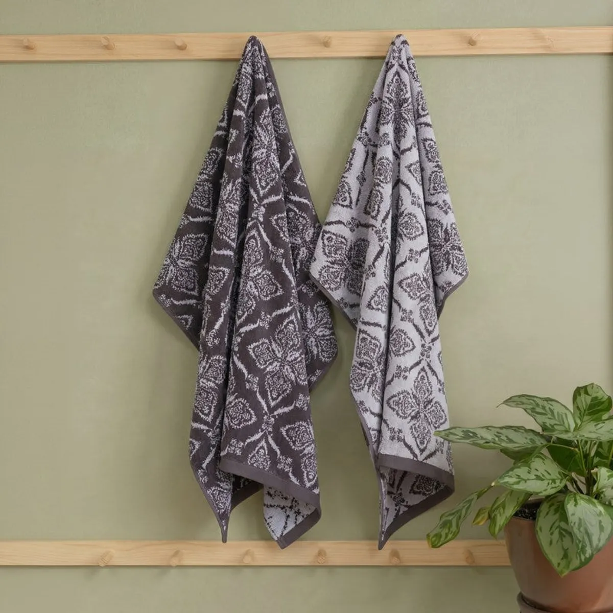 Grey floral bath towel hanging on a wooden bathroom rack