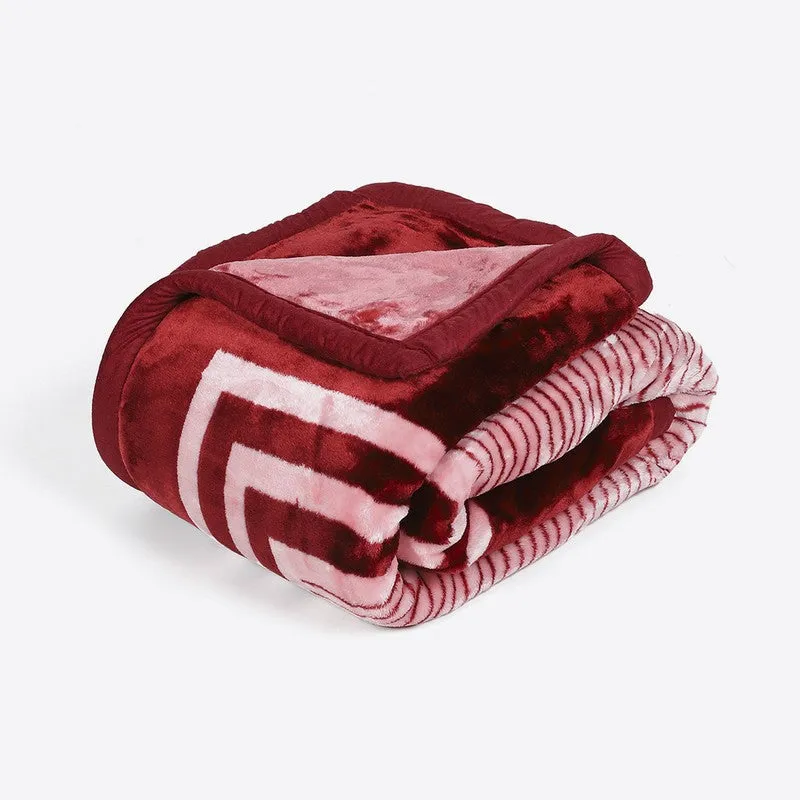 Folded maroon and pink geometric blanket showing its patterned layers