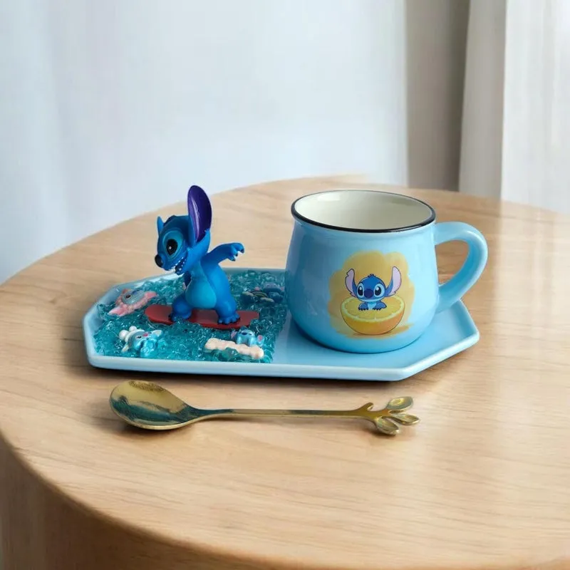 Blue ceramic character mug, figurine, tray and decorative spoon displayed on a round wooden table