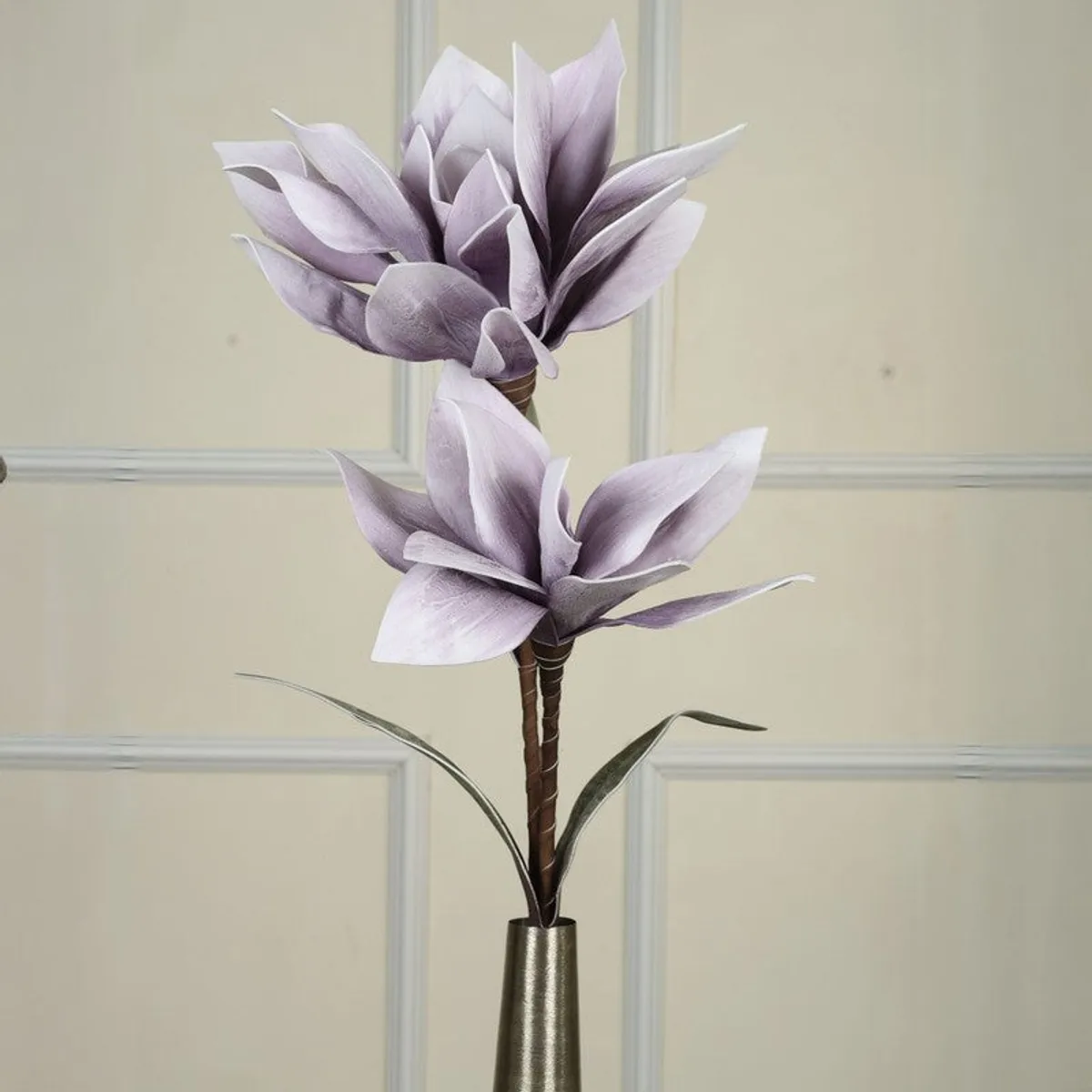 Close view of two purple artificial flowers and slender green leaves