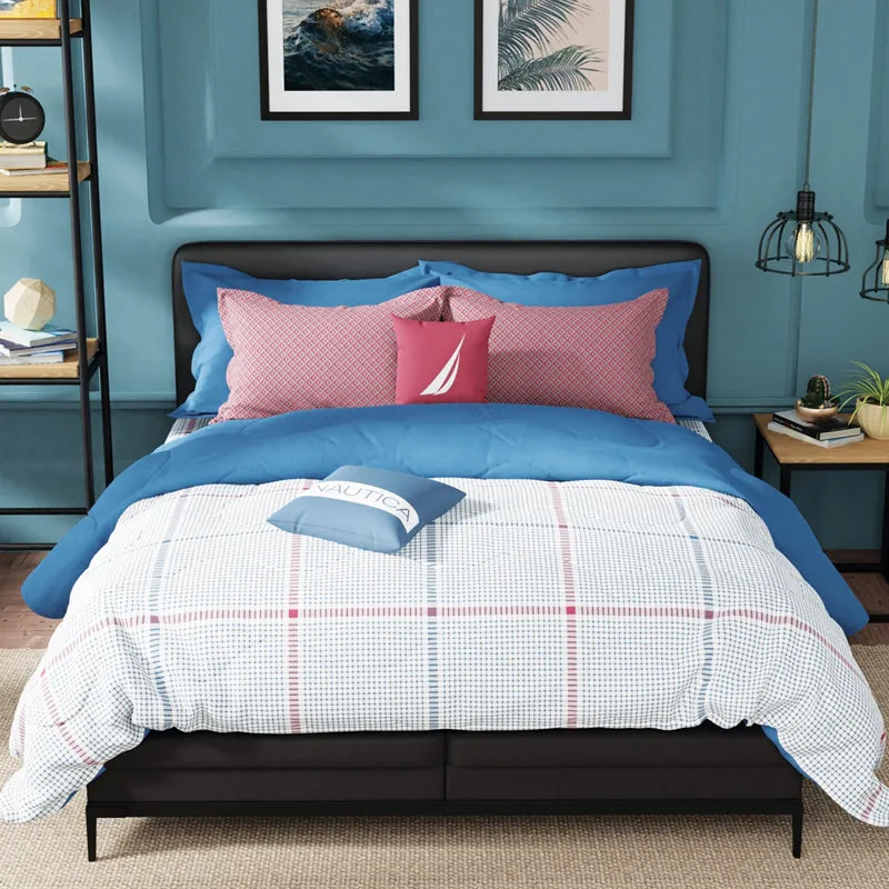Bed styled with the blue and red checked bedsheet in a modern room