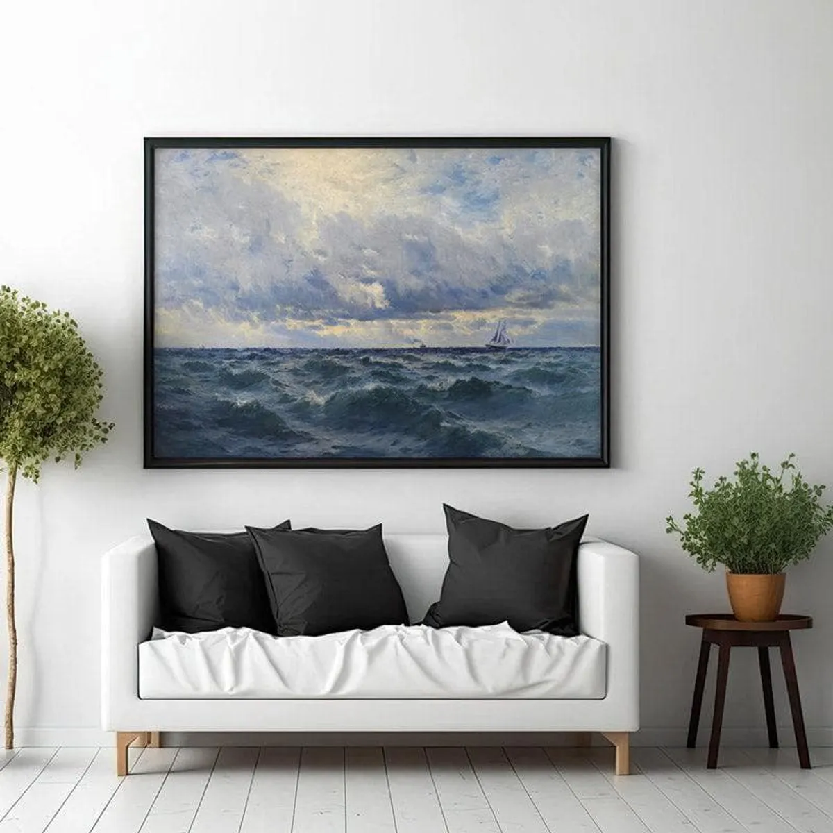 Large framed seascape artwork hung above a white sofa with black cushions.