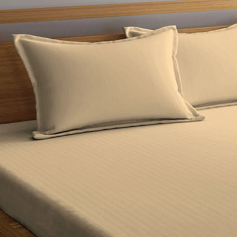 Cream striped bedsheet with matching pillow covers on a wooden bed
